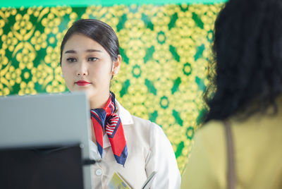 At the airport check-in counter, a passenger hands over his documents to the manager via a counter 