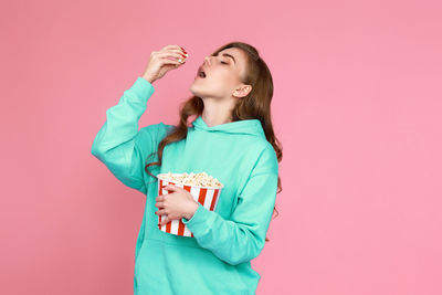 Portrait of smiling young woman against pink background