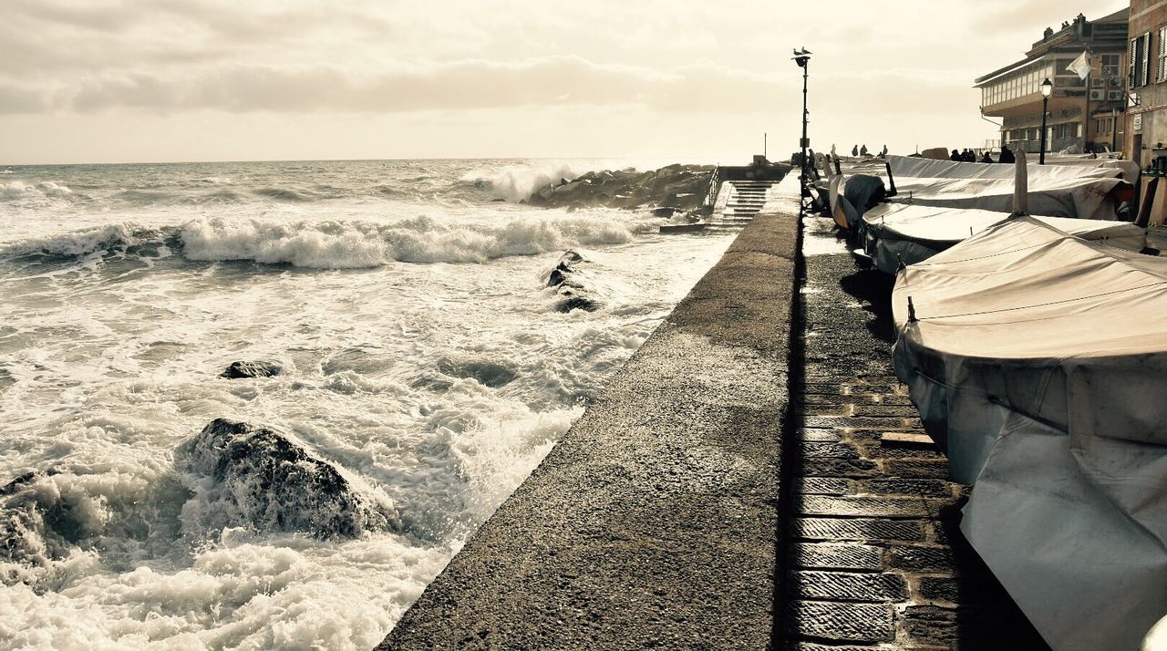 sea, lifestyles, water, sky, beach, men, leisure activity, person, shore, sand, horizon over water, cloud - sky, walking, built structure, incidental people, building exterior, sunlight