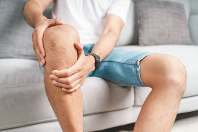 Low section of man sitting on sofa at home