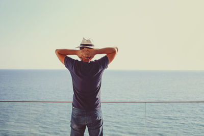 Rear view of woman standing by sea against clear sky