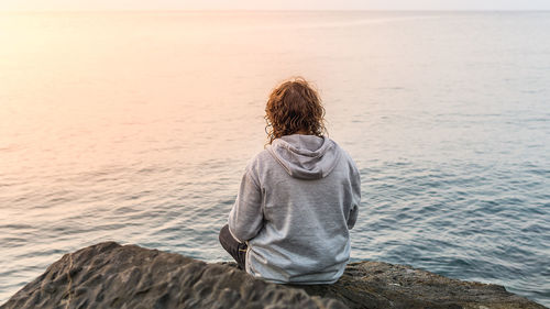 Rear view of woman sitting at beach