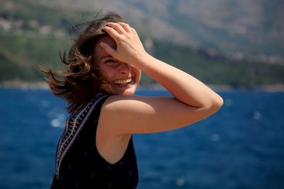 Portrait of smiling young woman against sea