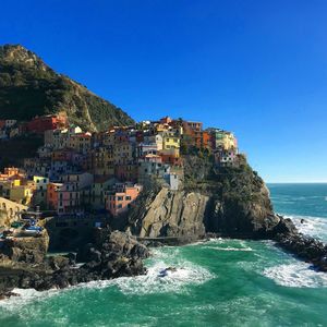 Scenic view of sea by cliff against clear blue sky