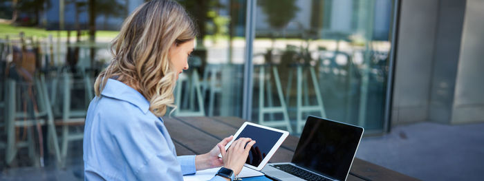 Young woman using laptop while standing in cafe