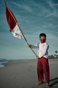 Boy standing on beach against sky