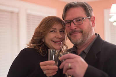 Portrait of mature couple toasting drink at home