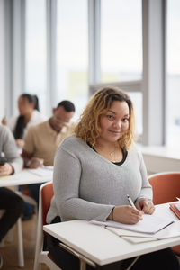 Portrait of woman making notes in class