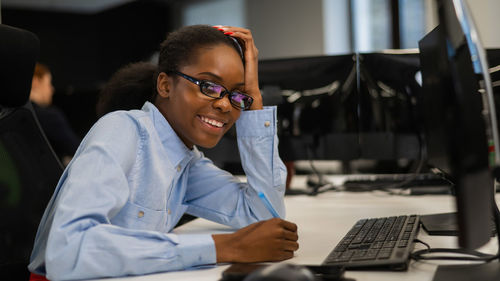 Young woman using mobile phone while sitting in office