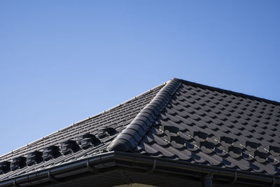 Low angle view of roof of building against clear blue sky