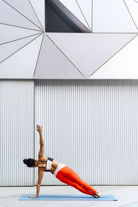 Mid adult female sportsperson practicing side plank on exercise mat