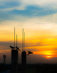 Silhouette built structure against dramatic sky during sunset