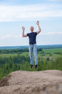 Full length of man standing on rock against sky