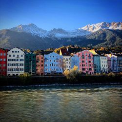 Houses by snowcapped mountains against clear sky