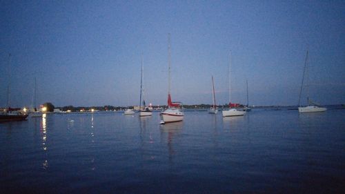 Sailboats moored on sea against clear sky