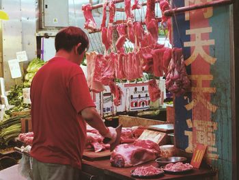 Rear view of butcher cutting meat at market