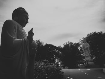 Man statue against trees and sky