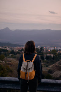 Rear view of woman standing on landscape against sky