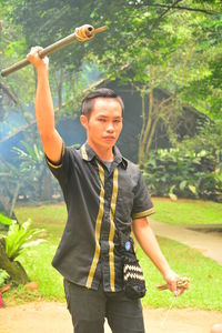 Full length of young man standing by tree