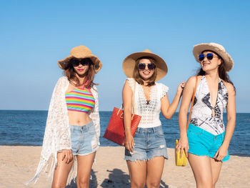 Young woman wearing sunglasses on beach against sky