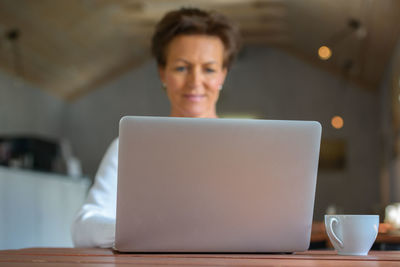 Midsection of woman using mobile phone while sitting on table