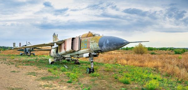 Abandoned airplane on field against sky