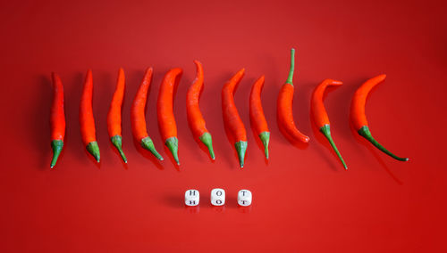 Close-up of red chili pepper on table against orange wall