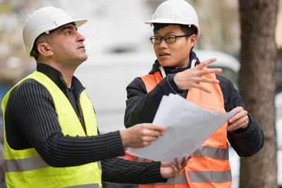 Engineers discussing while standing at construction site