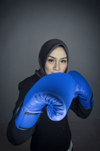 Portrait of young woman standing against blue background