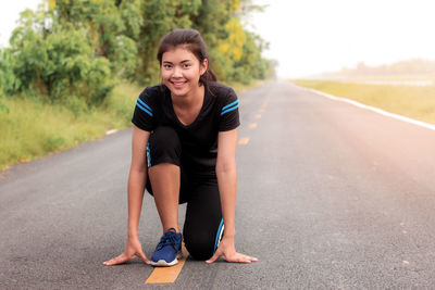 Portrait of smiling woman kneeling on road