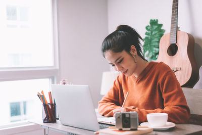 Young woman using mobile phone while sitting on table