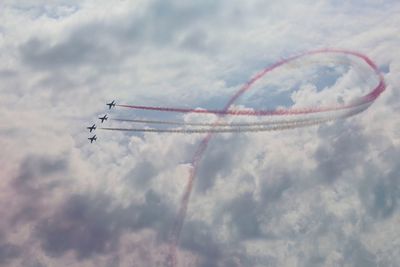 Low angle view of airshow against cloudy sky