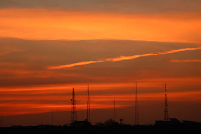 Silhouette electricity pylon against dramatic sky during sunset