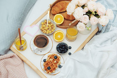 Romantic breakfast with coffee, waffles, orange juice and rose flowers.