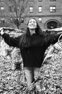 Young woman holding shawl while standing at park during autumn