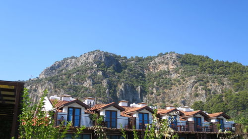 Houses amidst trees and buildings against clear blue sky