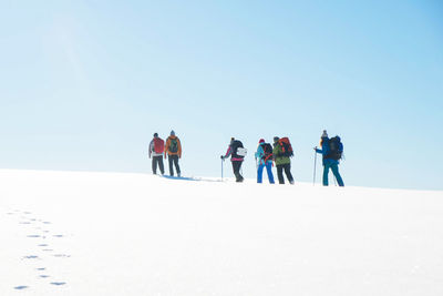 People on snow covered land against clear sky