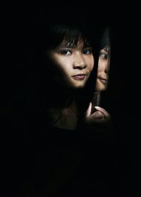 Portrait of smiling young woman with kitchen knife in darkroom