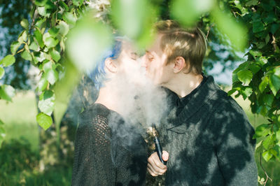 Young couple kissing while exhaling smoke