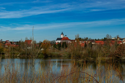 Scenic view of lake by buildings against blue sky