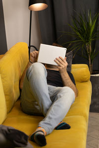 Midsection of man using mobile phone while sitting on sofa at home