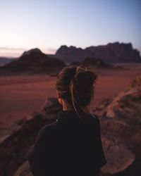 Rear view of woman standing on desert against clear sky