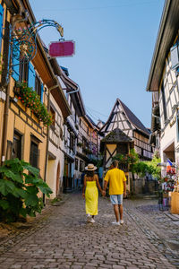 Rear view of people walking on street amidst buildings