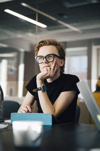 Businesswoman discussing with transgender colleague over laptop in board room during meeting