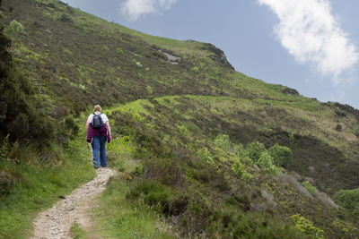  back view of a lady hiker with backpack walking along devon coast path, travel concept, vacation.