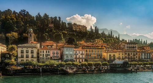 Buildings by river against sky in city