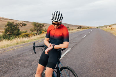 Female cyclist standing on road