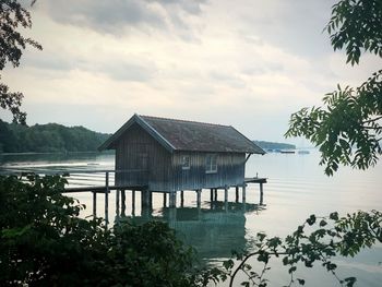 House by lake against sky