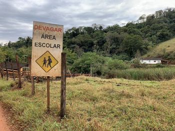 Information sign on field by road against sky