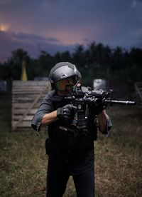 Rear view of man standing on field with weapons and equipment at night